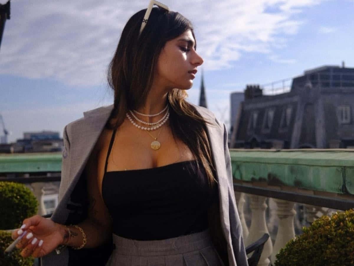 a woman in a grey jacket and skirt standing on a balcony — 1200x900 wallpaper