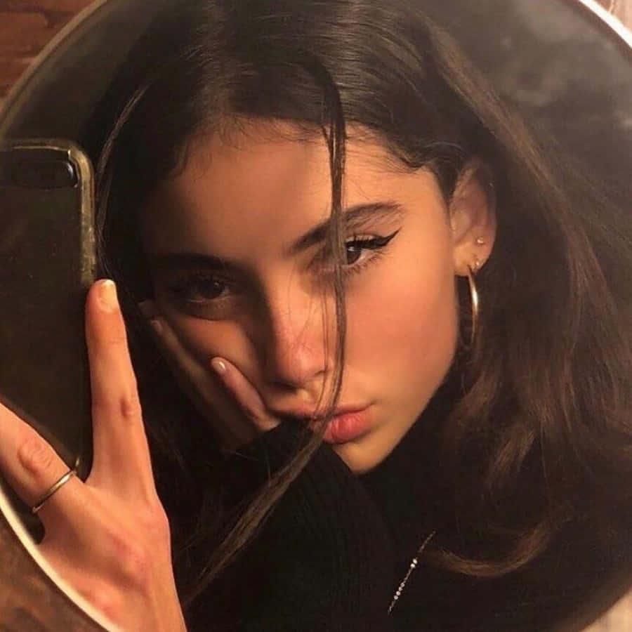 A young woman looks effortlessly beautiful in her natural makeup, wearing an ivory cardigan and green dress. — 900x900 wallpaper