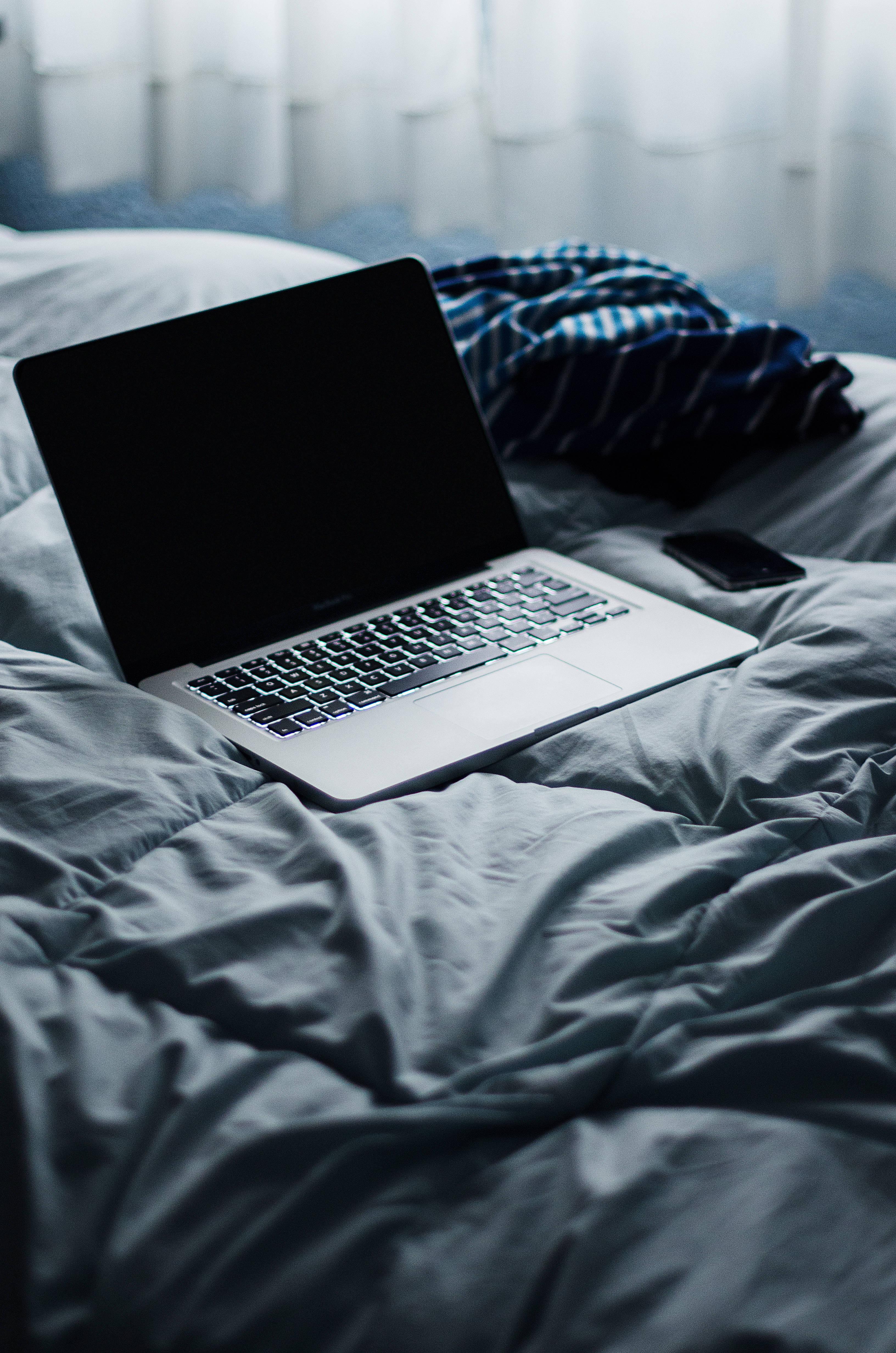 A silver MacBook Pro on a white desk with an illuminated keyboard and a dark background — 3264x4928 wallpaper