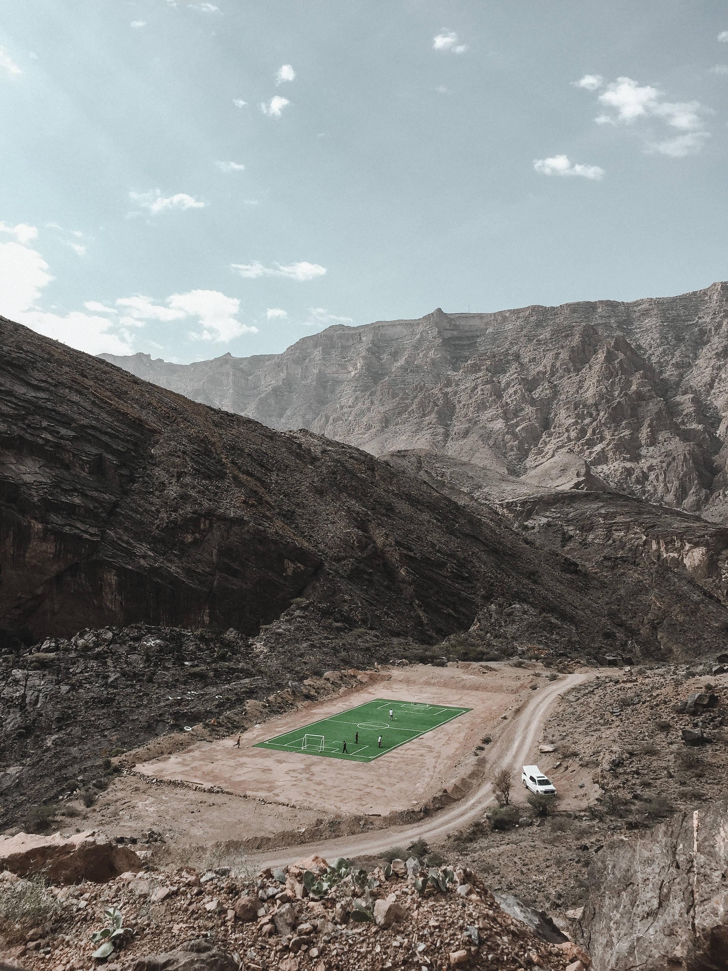 From high atop the mountain range, get a glimpse of a football stadium below — 2448x3264 wallpaper