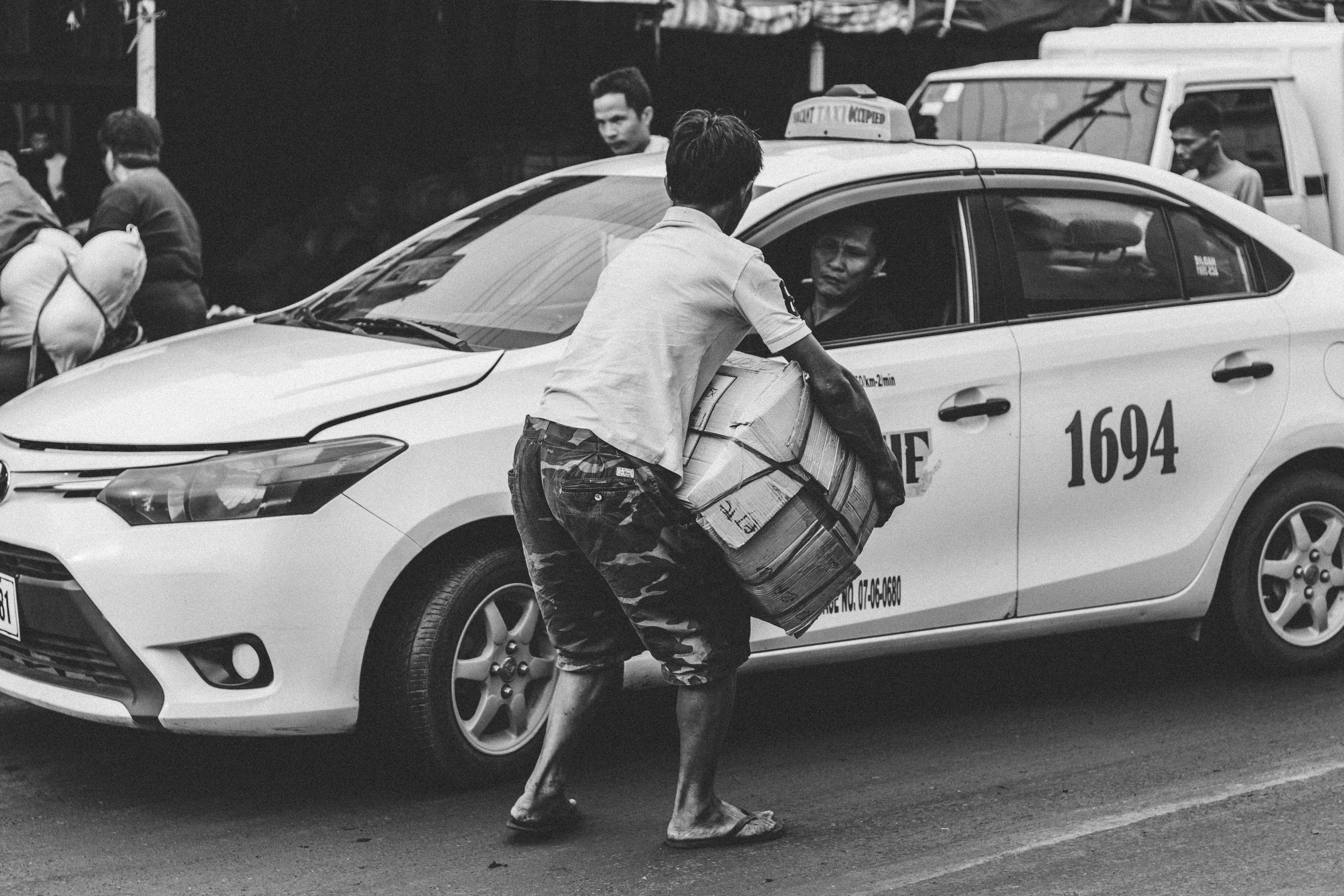 Greyscale Photography Of Man Carrying Cardboard Box Beside Taxi — 6000x4000 wallpaper