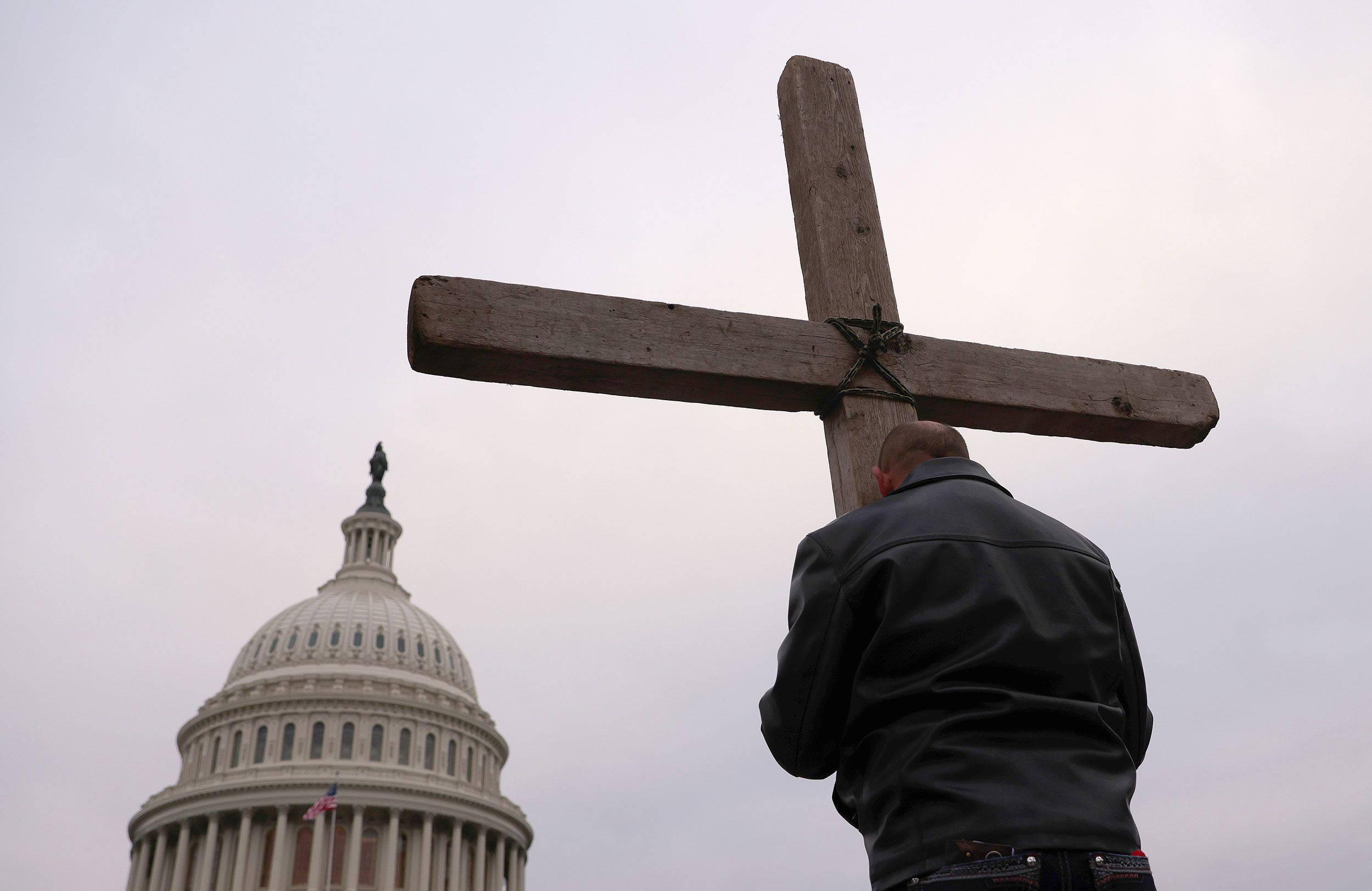 Man Clutching Christian Cross Symbols — 2500x1623 wallpaper