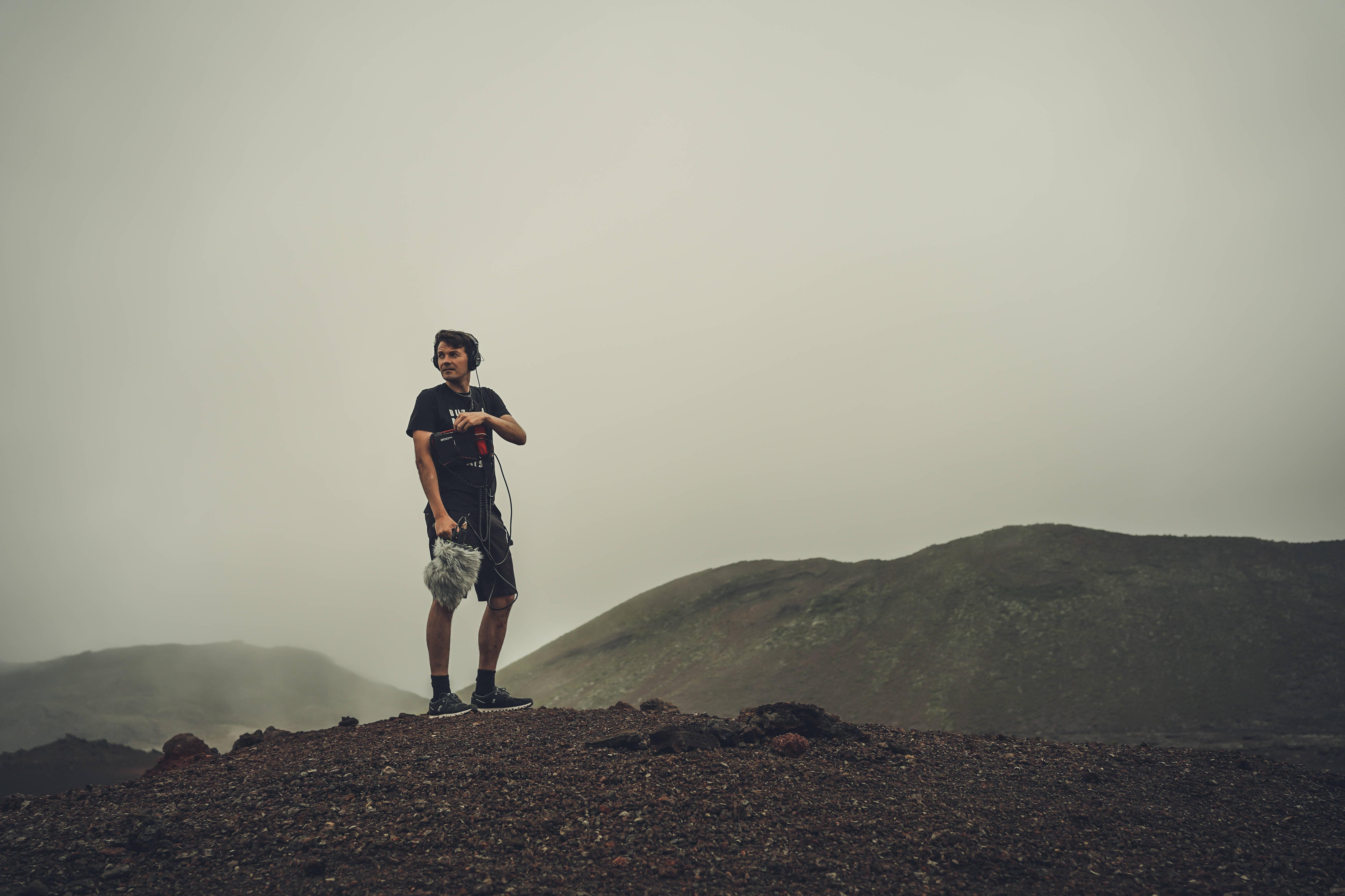 Man In Black T-shirt And Brown Shorts Standing On Brown Rock — 6000x4000 wallpaper