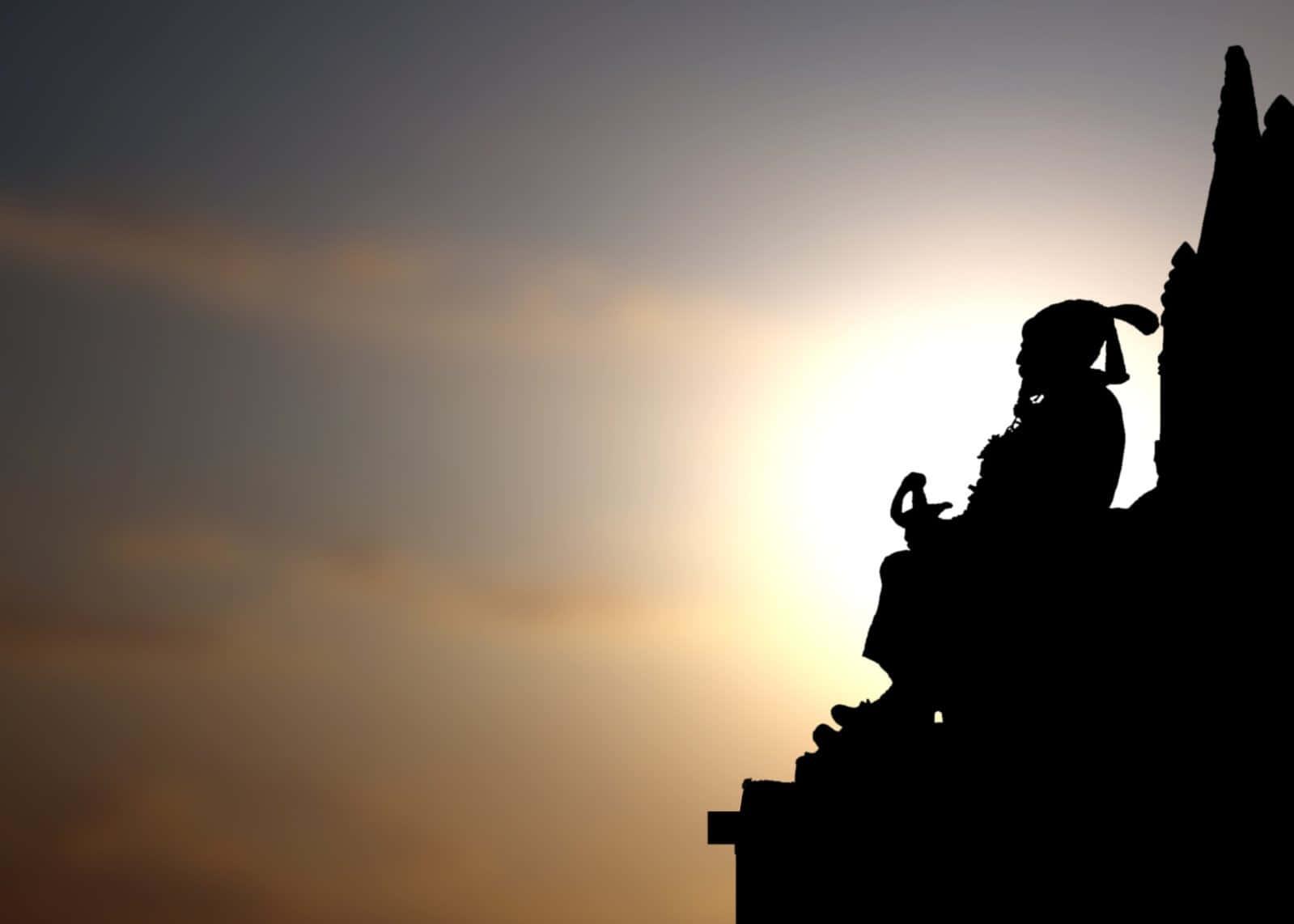 silhouette of a man sitting on top of a statue — 1599x1142 wallpaper