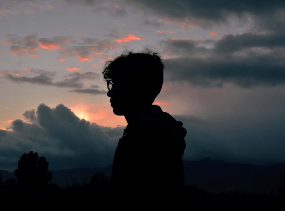 silhouette of a person standing in front of a sunset — 1000x740 wallpaper